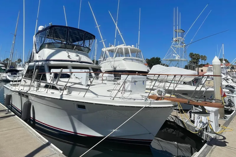1975 Uniflite Sport Fisher 42 yacht docked at marina under clear blue sky.