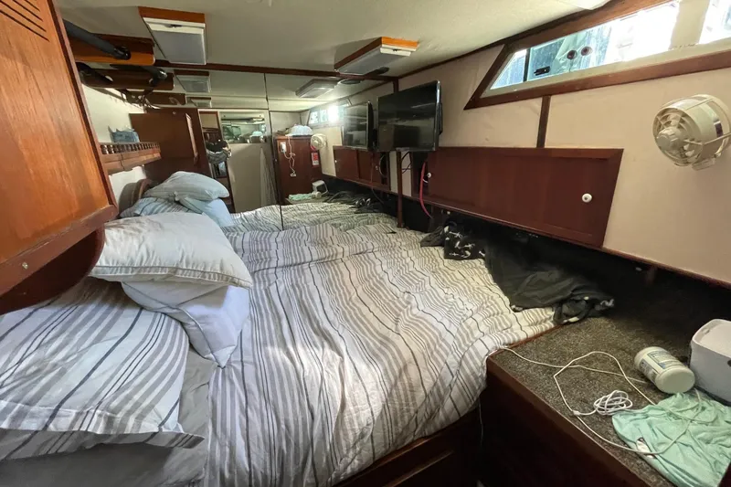 1975 Uniflite Sport Fisher 42 cabin interior with bed, pillows, and wooden storage.