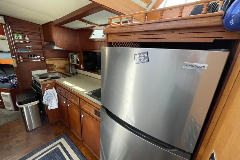 1975 Uniflite Sport Fisher 42 yacht kitchen with Frigidaire fridge and wooden cabinetry.
