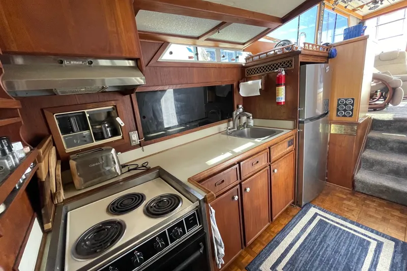 1975 Uniflite Sport Fisher 42 kitchen with stove, sink, and refrigerator in wooden interior.