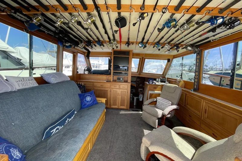 Interior of a 1975 Uniflite Sport Fisher 42 with fishing rods and cozy seating.