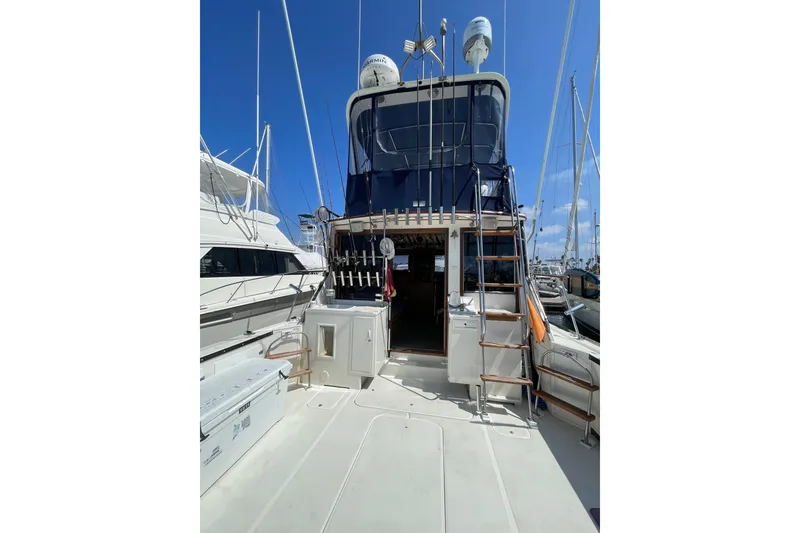 1975 Uniflite Sport Fisher 42 yacht docked, featuring fishing rods and equipment under a clear blue sky.
