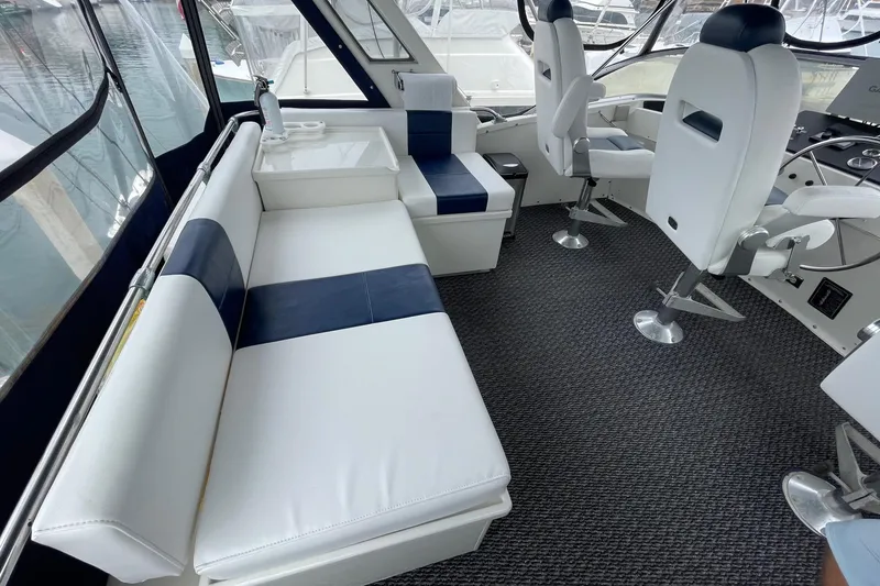 1975 Uniflite Sport Fisher 42 interior with white and navy seating, helm chairs, and carpeted floor.