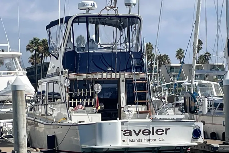 1975 Uniflite Sport Fisher 42 docked at marina, featuring blue canopy and fishing equipment.