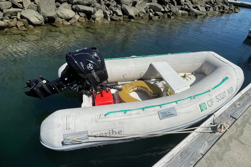 Inflatable boat with Tohatsu motor docked by rocky shore, 1975 Uniflite Sport Fisher 42.