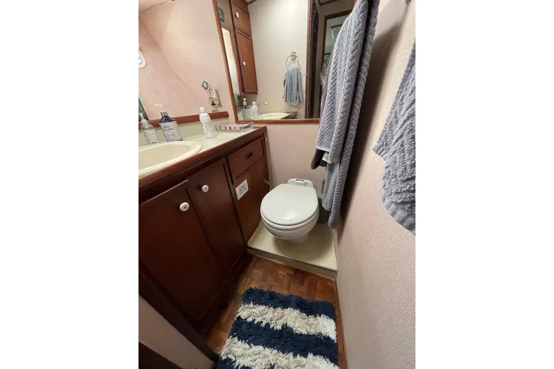 1975 Uniflite Sport Fisher 42 bathroom with wooden cabinets and nautical decor.