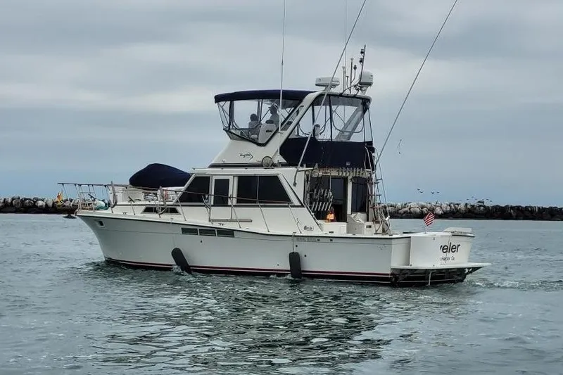 1975 Uniflite Sport Fisher 42 boat on water, overcast sky, American flag displayed.