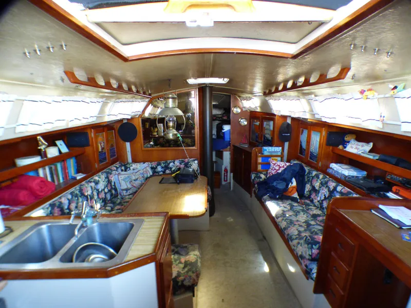 Interior of 1982 Catalina 38 sailboat with cozy seating and wooden cabinetry.