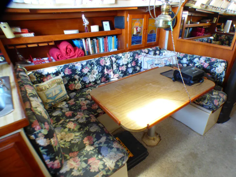 Cozy interior of 1982 Catalina 38 sailboat with floral upholstery and wooden table.