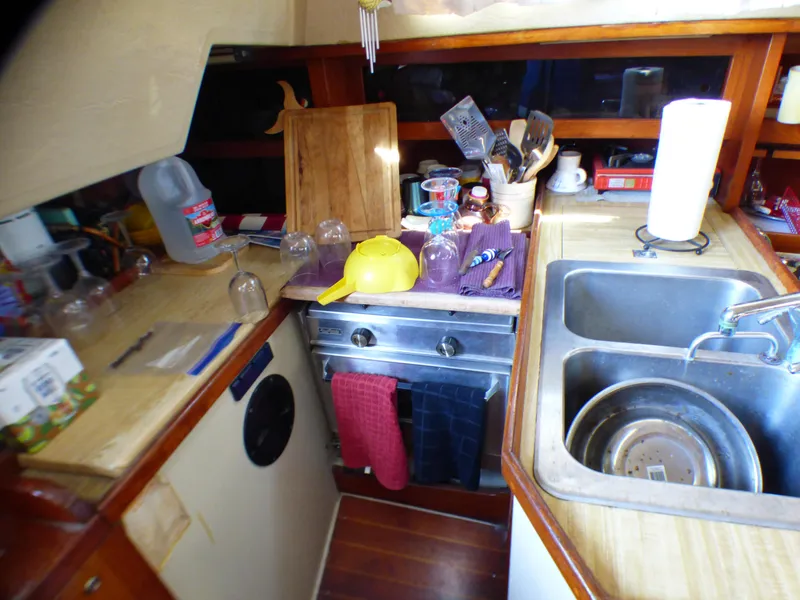 Compact kitchen in a 1982 Catalina 38 sailboat with stove, sink, and utensils.