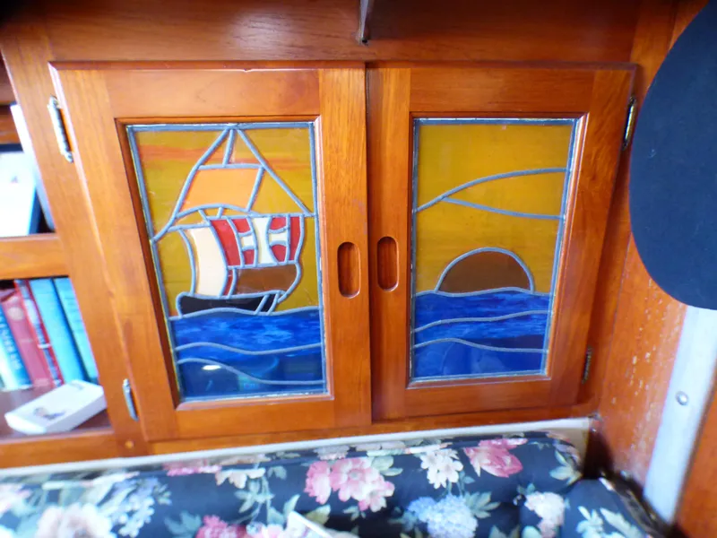 Stained glass cabinet doors on 1982 Catalina 38, featuring nautical ship and sunset design.