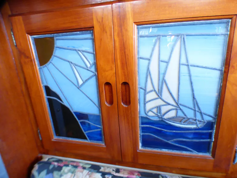 Stained glass cabinet doors on 1982 Catalina 38, featuring sailboat and sun design.