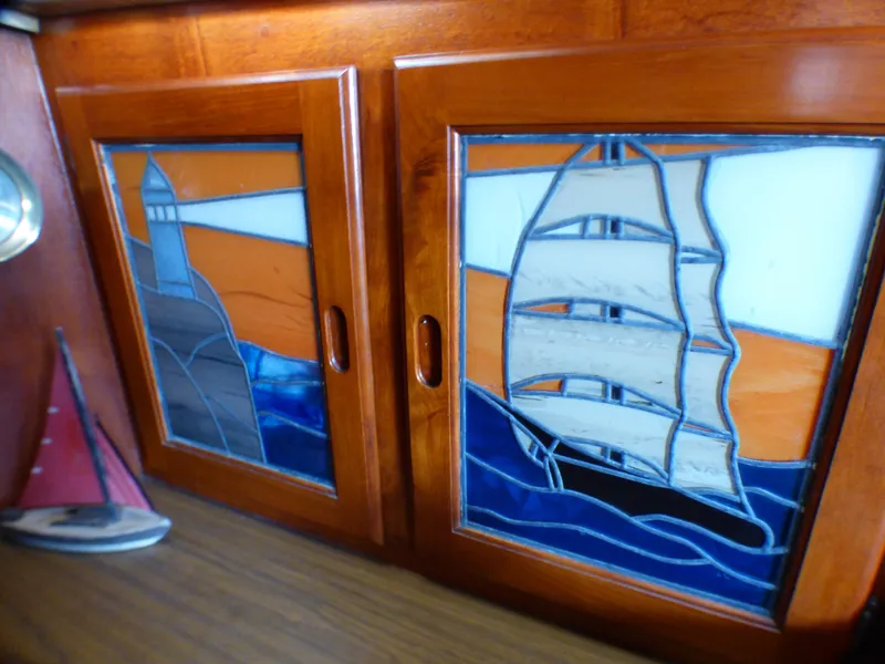 Stained glass cabinet doors on 1982 Catalina 38 sailboat, featuring lighthouse and sailboat designs.