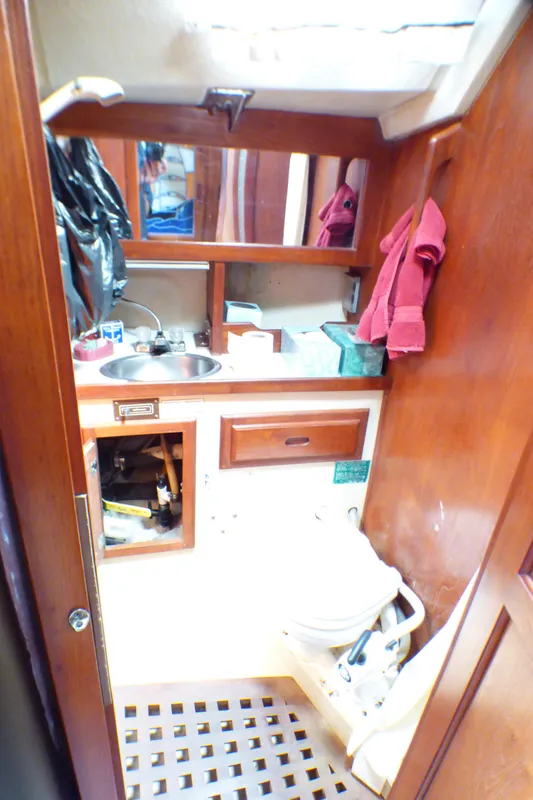 1982 Catalina 38 yacht bathroom with wooden cabinetry, sink, and toilet.