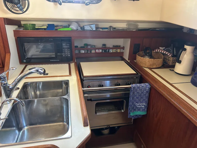 Compact galley kitchen in a 1998 Island Packet 350 sailboat with sink, stove, and microwave.