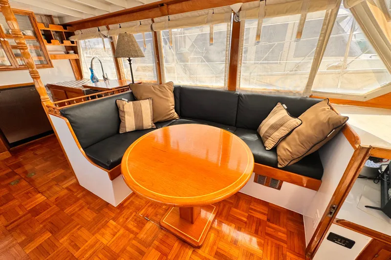 Cozy seating area in a 1978 Roughwater 41 boat with wooden table and cushions.