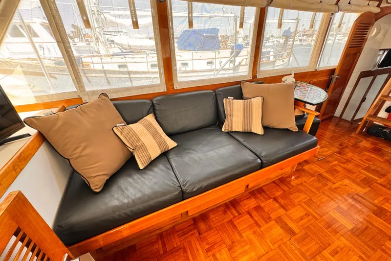 Interior of 1978 Roughwater 41 yacht with black leather sofa and decorative pillows.