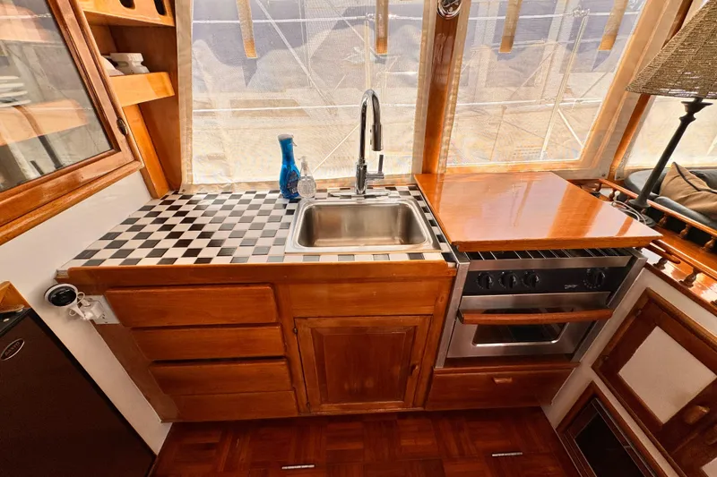 1978 Roughwater 41 yacht kitchen with wood cabinetry, sink, stove, and checkered countertop.