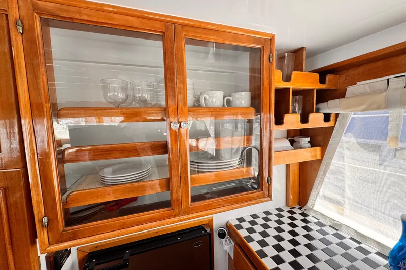 1978 Roughwater 41 yacht interior with wooden cabinets, glassware, and checkered countertop.