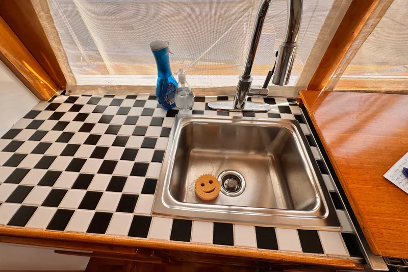 1978 Roughwater 41 boat kitchen sink with checkered countertop and cleaning supplies.