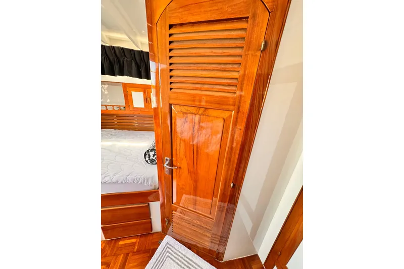 Wooden cabin interior of 1978 Roughwater 41 boat, featuring a polished door and cozy bed.