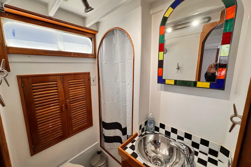 1978 Roughwater 41 boat bathroom with colorful mirror, stainless sink, and wooden accents.