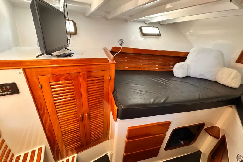 1978 Roughwater 41 boat interior with wooden cabinetry, cushioned seating, and mounted TV.