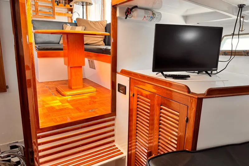 1978 Roughwater 41 yacht interior with wooden dining area and TV setup.