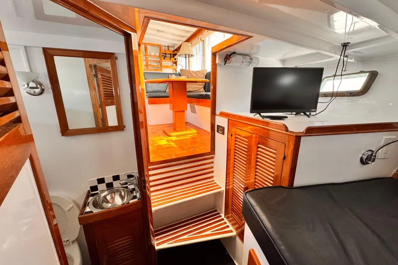 Interior of 1978 Roughwater 41 boat featuring wooden cabinetry, seating area, and mounted TV.