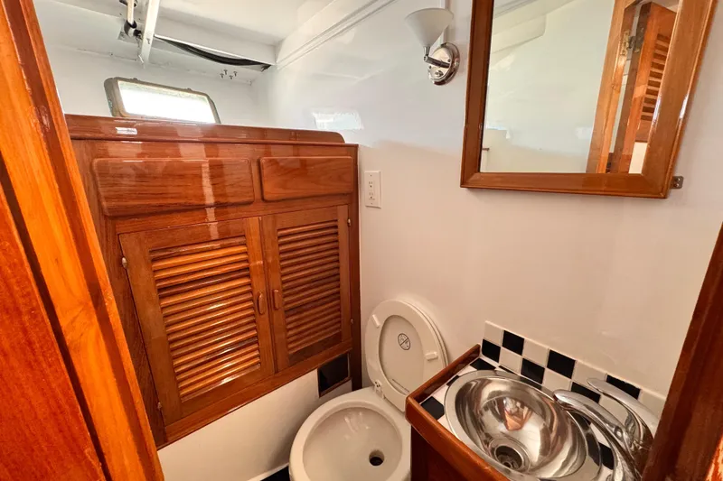 1978 Roughwater 41 yacht bathroom with wooden cabinets and stainless steel sink.