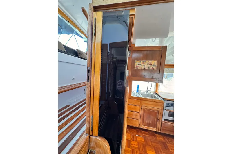Interior view of 1978 Roughwater 41 boat, featuring wooden cabinetry and kitchen area.