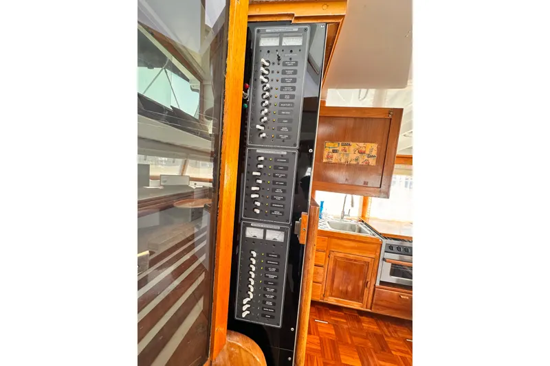 Electrical panel inside a 1978 Roughwater 41 boat, featuring wooden cabinetry and kitchen area.