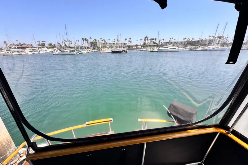 View from 1978 Roughwater 41 boat, overlooking marina with sailboats and clear blue sky.
