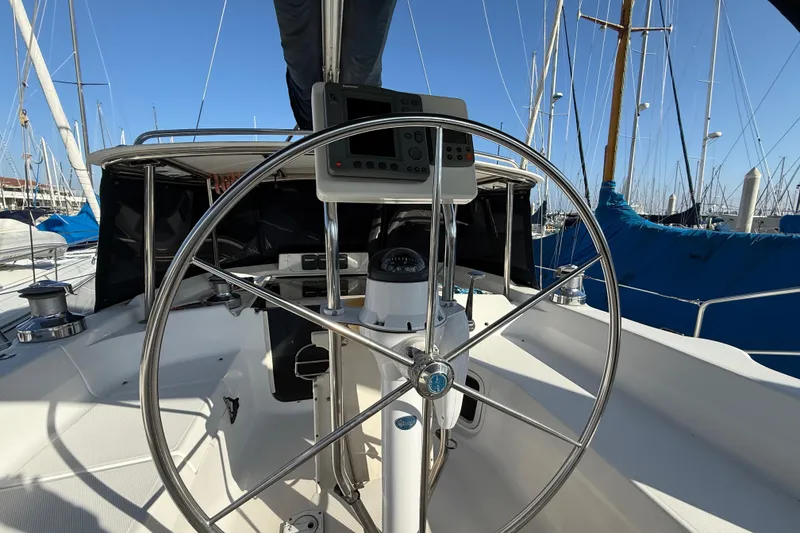 Steering wheel of 1999 Hunter Passage 420 sailboat in marina setting.