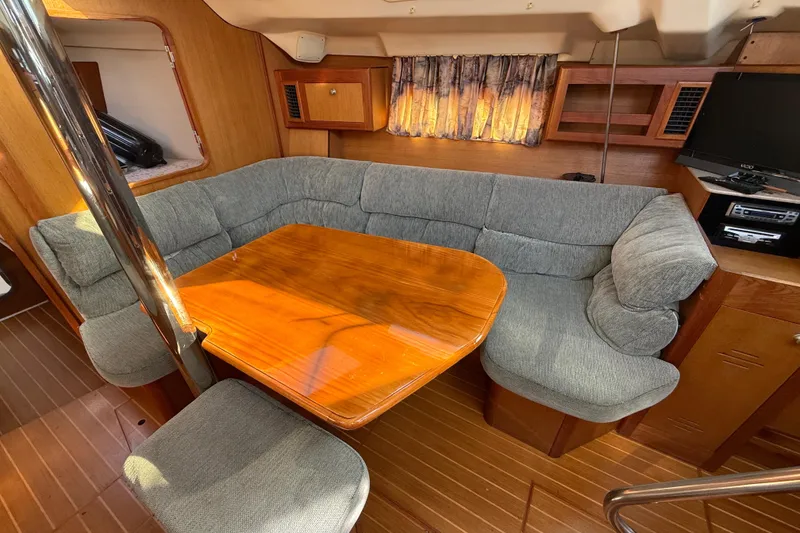 Cozy interior of 1999 Hunter Passage 420 yacht with wooden table and cushioned seating.