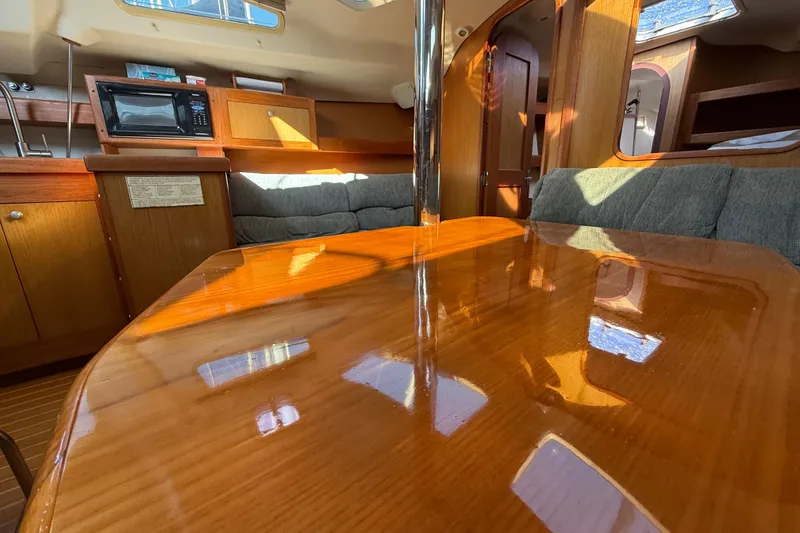 Interior of 1999 Hunter Passage 420 yacht with polished wood table and cozy seating.