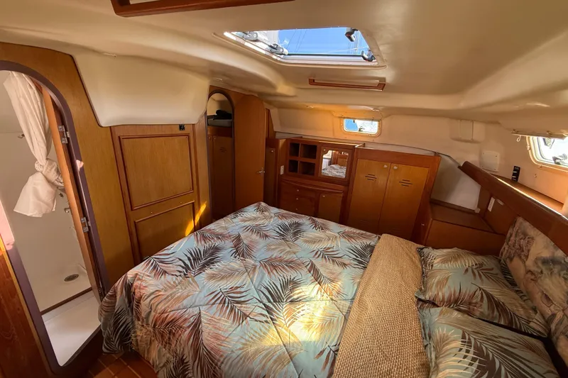 1999 Hunter Passage 420 yacht interior with cozy bedroom, wooden cabinets, and skylight.