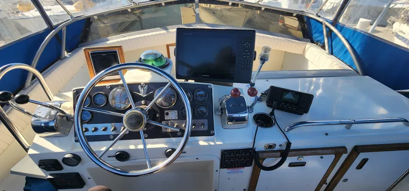 1985 Bertram 33 Flybridge Cruiser helm with steering wheel, gauges, and navigation equipment.