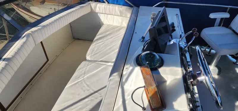 1985 Bertram 33 Flybridge Cruiser helm with white seating and navigation equipment.