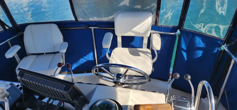 1985 Bertram 33 Flybridge Cruiser helm with white seating and steering wheel.