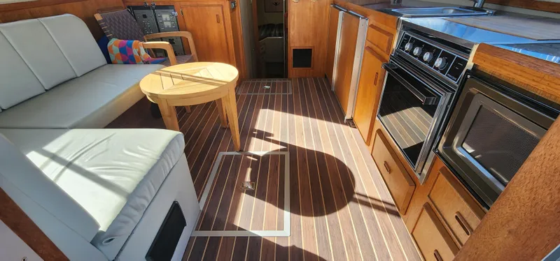 Interior of 1985 Bertram 33 Flybridge Cruiser with wood flooring and kitchen amenities.