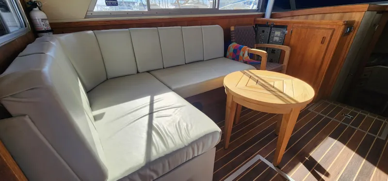 1985 Bertram 33 Flybridge Cruiser interior with cushioned seating and wooden table.