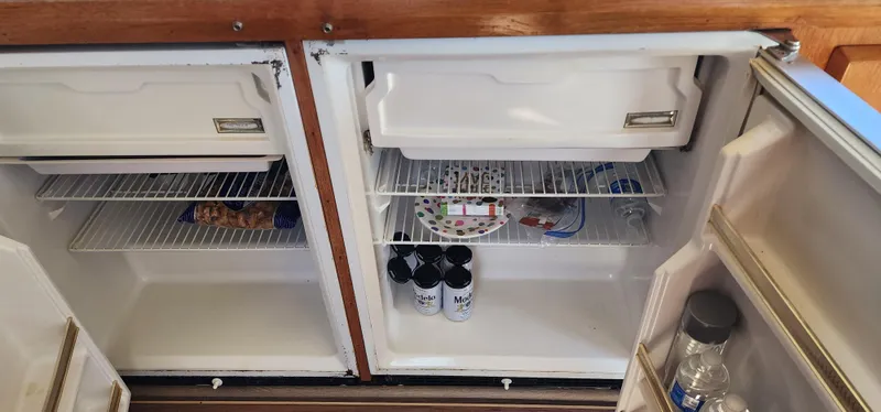 Open fridge on 1985 Bertram 33 Flybridge Cruiser with drinks and snacks inside.