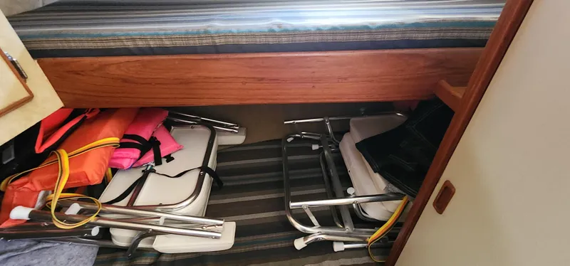 Interior storage of 1985 Bertram 33 Flybridge Cruiser with life jackets and folding chairs.