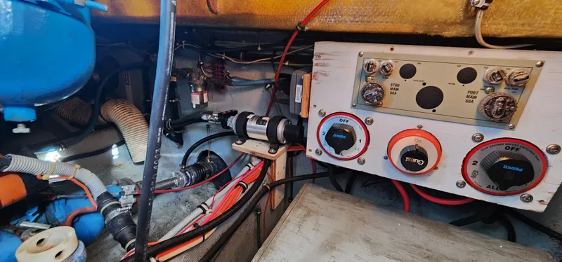 Engine room of a 1985 Bertram 33 Flybridge Cruiser, showcasing wiring and control panel.
