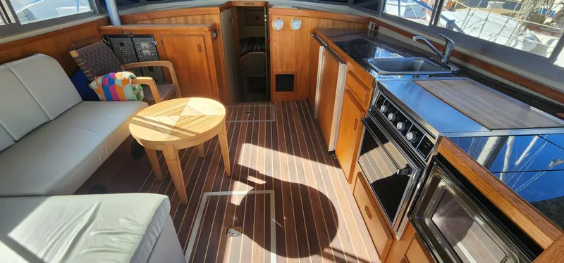 1985 Bertram 33 Flybridge Cruiser interior with wood finish, kitchenette, and seating area.