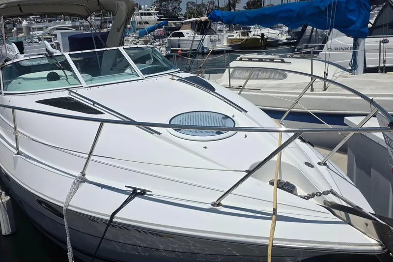 2001 Doral 250se boat docked at a marina, featuring sleek white design and spacious deck.
