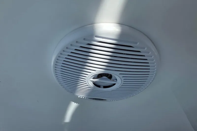 White speaker on a 2001 Doral 250se boat ceiling, illuminated by sunlight.