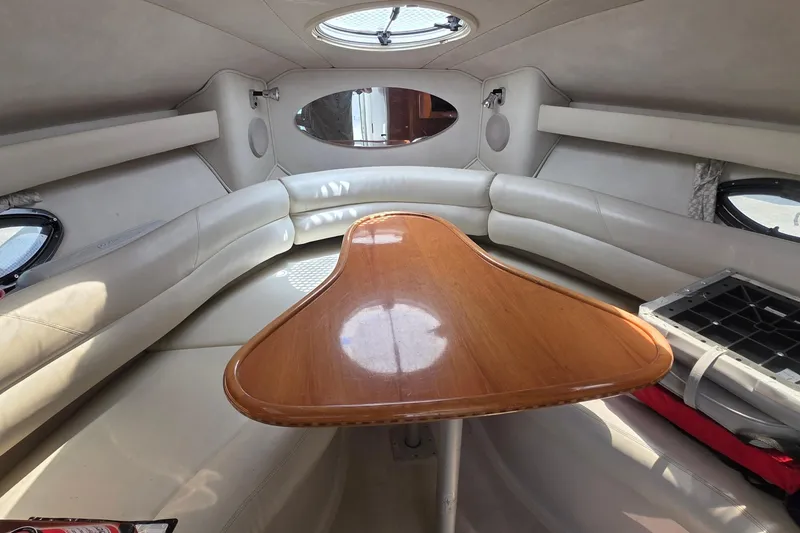 Interior of a 2001 Doral 250se boat with a wooden table and cushioned seating.