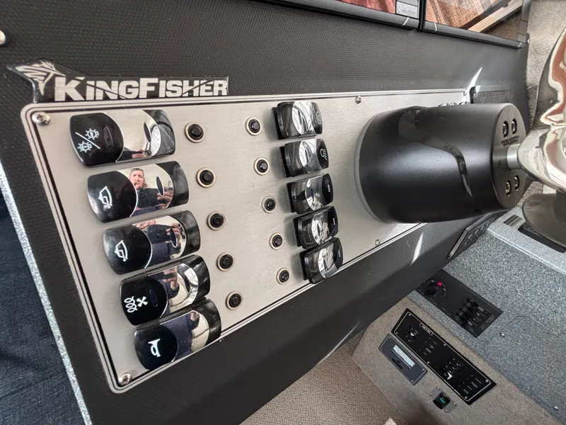 Control panel of 2023 KingFisher 3025 Destination boat with labeled switches and steering wheel.